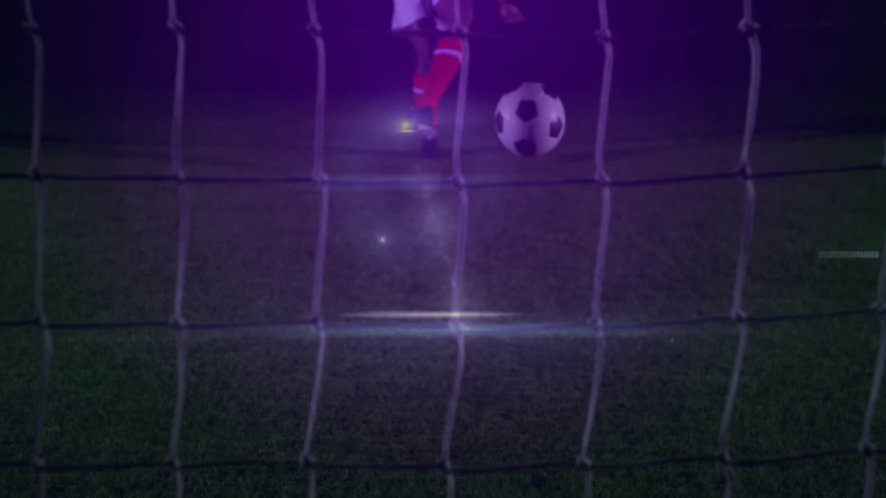 Pemain sepak bola pria menggiring bola ke gawang di bawah lampu sorot di lapangan, dengan ikon teknologi animasi.