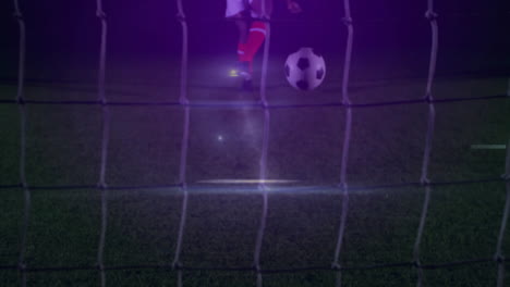 male soccer player charging ball at net under floodlights on pitch, with animated technology icons