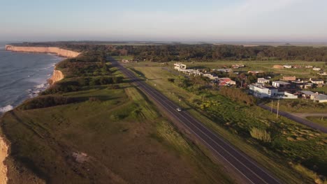 Autofahren-Auf-Küstenstraße-Neben-Meer,-Klippen-Und-Grünem-Wald-Während-Des-Sonnenuntergangs-In-Mar-Del-Plata,-Argentinien---Luftaufnahme