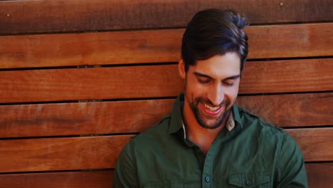 Man-using-mobile-phone-against-wooden-background-4k