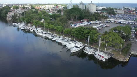 Varios-Yates-De-Lujo-Blancos-Están-Atracados-En-El-Puerto-De-Haina,-Mientras-Que-Las-Aguas-Tranquilas-Y-Tranquilas-Reflejan-La-Antena-De-Drones-Del-Cielo-Azul