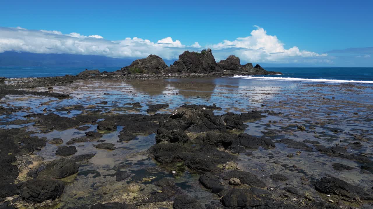 A stunning drone shot soars over the Baler Ocean, showcasing a majestic stone peak rising at the island’s corner, surrounded by crashing waves.