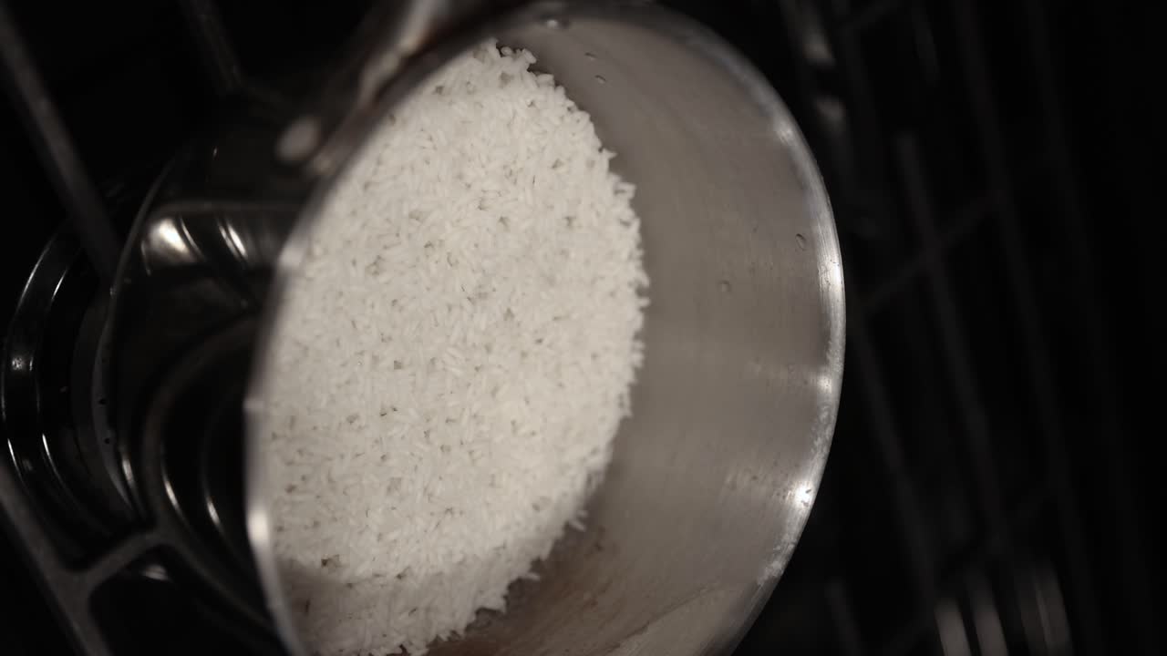 Vertical shot of person remove glass lid from shiny pot with white rice on stove