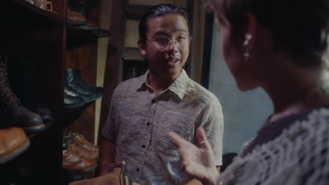 consignment store salesman telling about old leather boots to customer