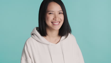 Asian-woman-in-sweater-smiling-on-camera.