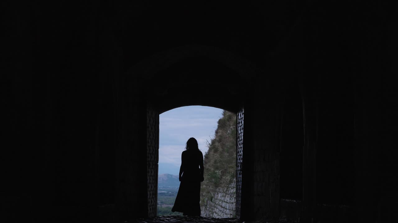 Silhouette of a woman in a dress coming out of a castle. Slow motion