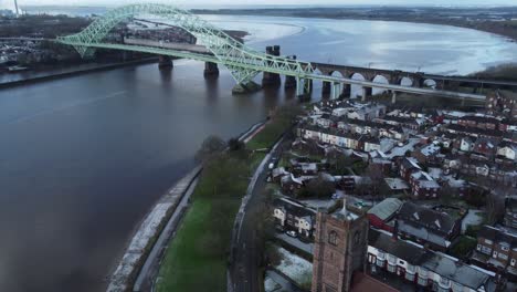 aerial view industrial small town frosty church rooftops neighbourhood north west england birdseye tilt up to jubilee bridge