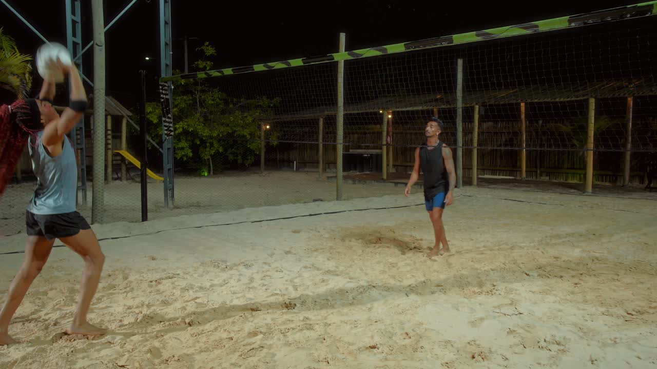 People playing beach volleyball at night
