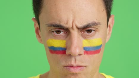 serious man with a colombian flag painted on the face
