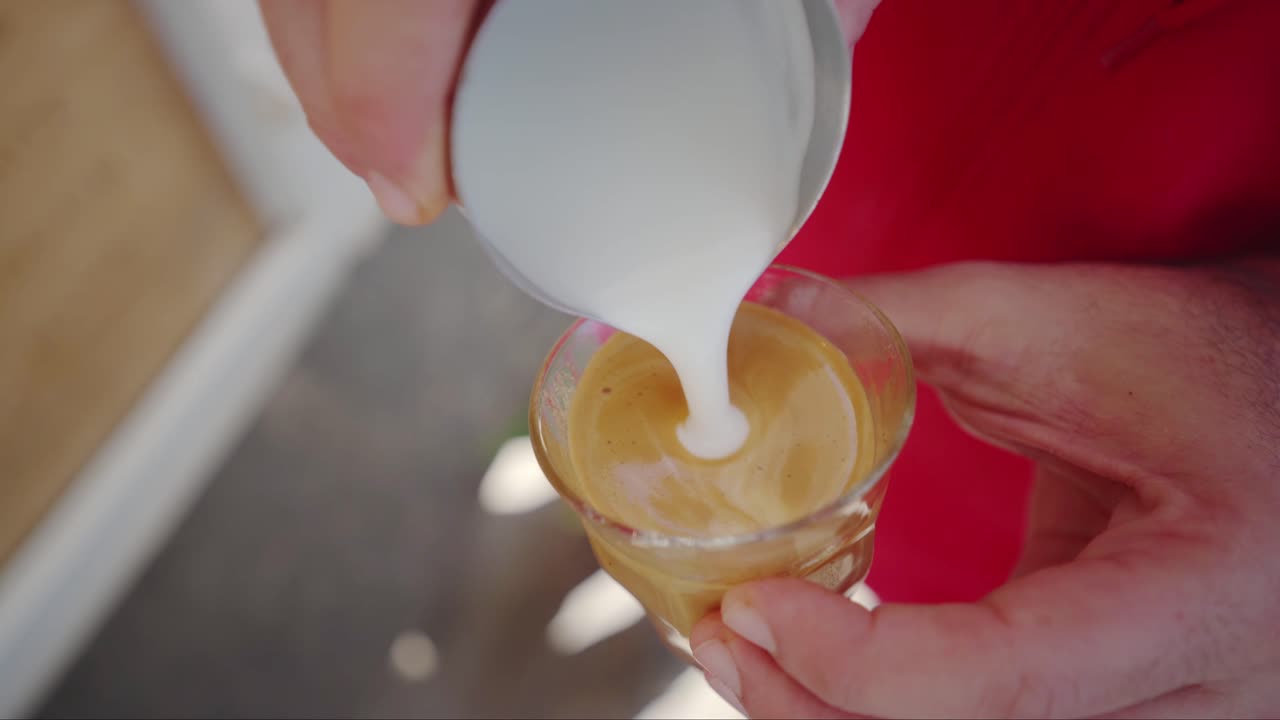 barista realizando arte con leche en la parte superior del café usando leche, primer plano de mano