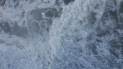 drone shot straight down of ocean waves washing around during high tide