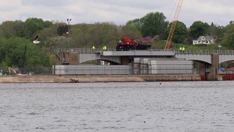 small crew of men operating a specialized crane to repair the dam rollers of lock and dam number 14 on the mississippi river near leclair iowa