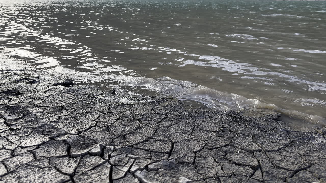 The cracked ground contrasts with the abundant water on the shores of the Kl&ouml;ntalersee lake Glarus Kanton, Switzerland