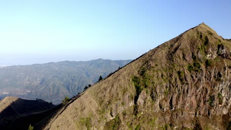 people descending the summit of mout batur active volcano in bali indonesia, aerial tilt down reveal shot