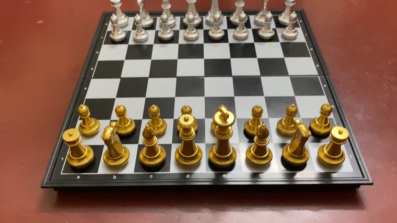 Metallic silver and golden chess pieces arranged on checkered board - Close up shot.