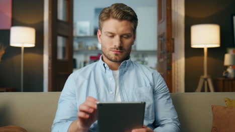 Focused businessman working sofa at home closeup. Calm guy using tab computer