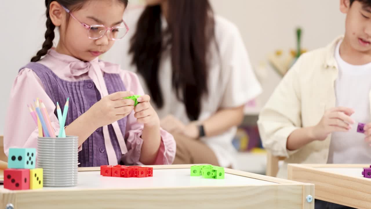 幼い女の子が、幼児教育の授業中にカラフルなプラスチックブロックをつなげることに集中しています。