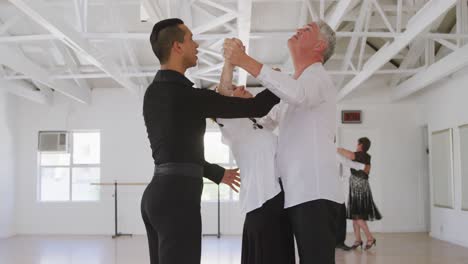 mixed race male dance teacher taking a ballroom dancing class at a dance studio