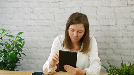 a stressed and frustrated young professional woman using a tablet in an office losing