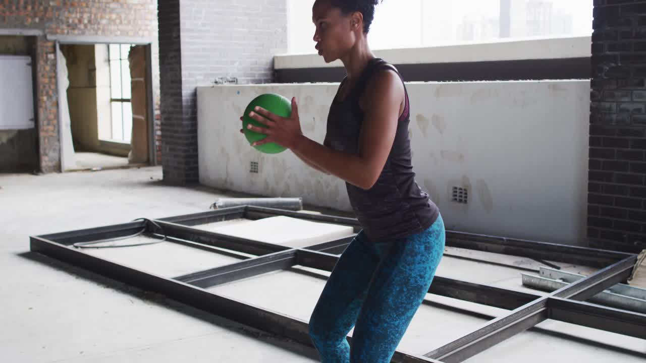 African american woman exercising with medicine ball in an empty urban building
