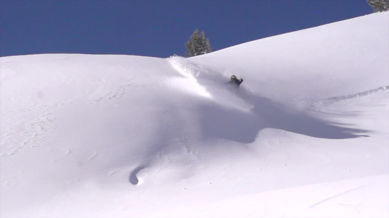 snowboard masculino banco de polvo vuelva backcountry polvo cámara lenta cinematográfica mediados del invierno nieve fresca cielos azules colorado en vail pass temprano en la mañana