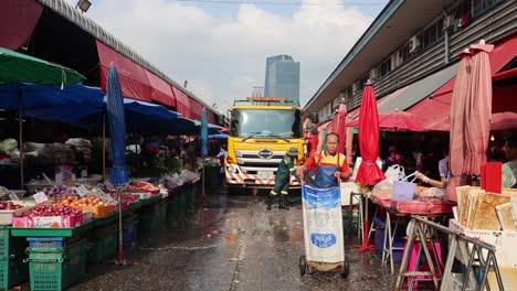 street cleaner washing down a busy market road