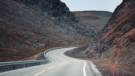 Drive-on-a-narrow-two-lane-road-between-slopes-covered-with-chipped-rocks-and-gravel