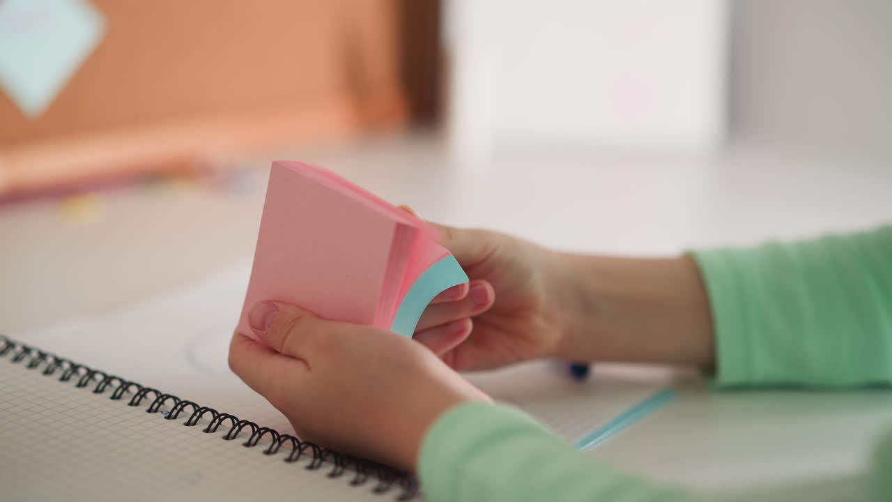 Little girl flips sticky papers in pack sitting at desk