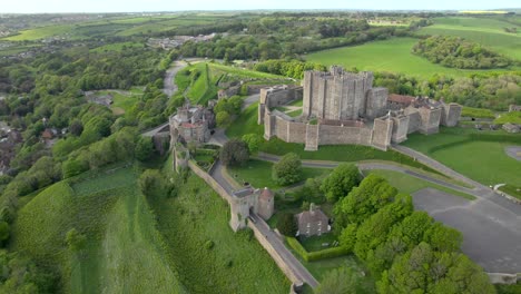 drone footage of dover castle in england, highlighting its stone fortifications and surrounding green hills, with winding roads visible below