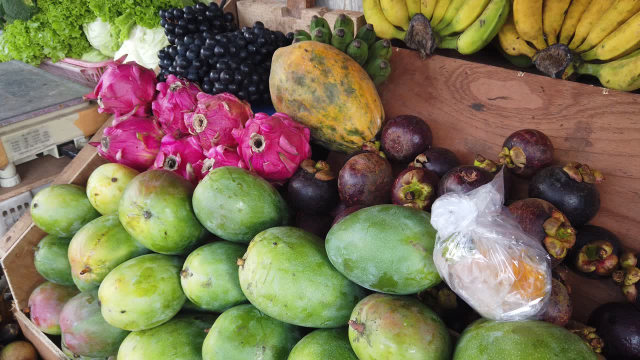Manghi, mangostani, frutto del drago, uva, banane, frutta tropicale esposta in un mercato del Sud-Est asiatico