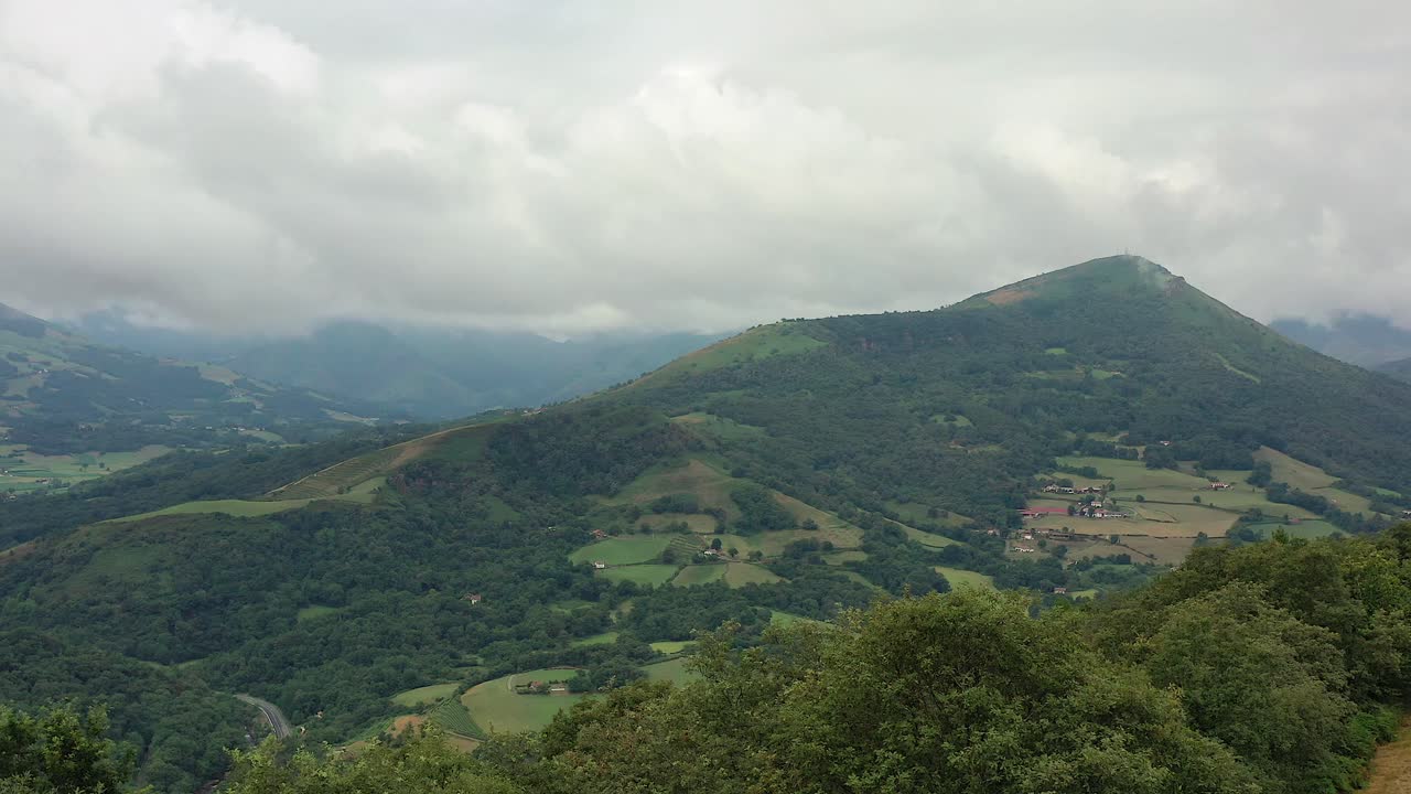 Flyover lush green agriculture hills of Ispoure France, overcast sky