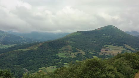 flyover lush green agriculture hills of ispoure france, overcast sky