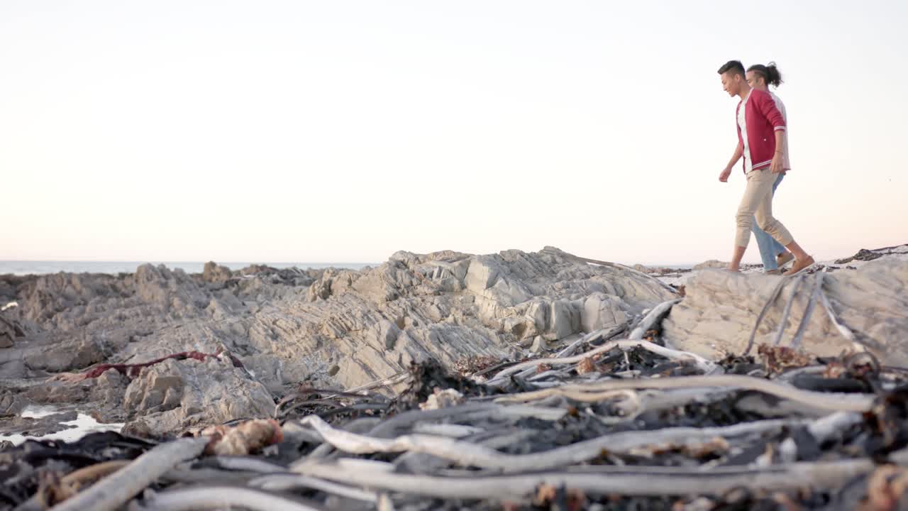 feliz pareja de hombres homosexuales diversos caminando por la playa, cámara lenta