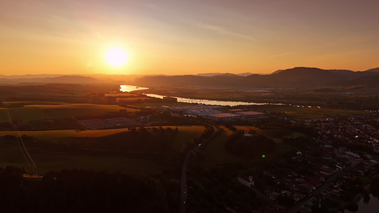 Soft warm orange light of setting sun spreading over the valley. Drone footage over the vast countryside of Slovakia at sunset.