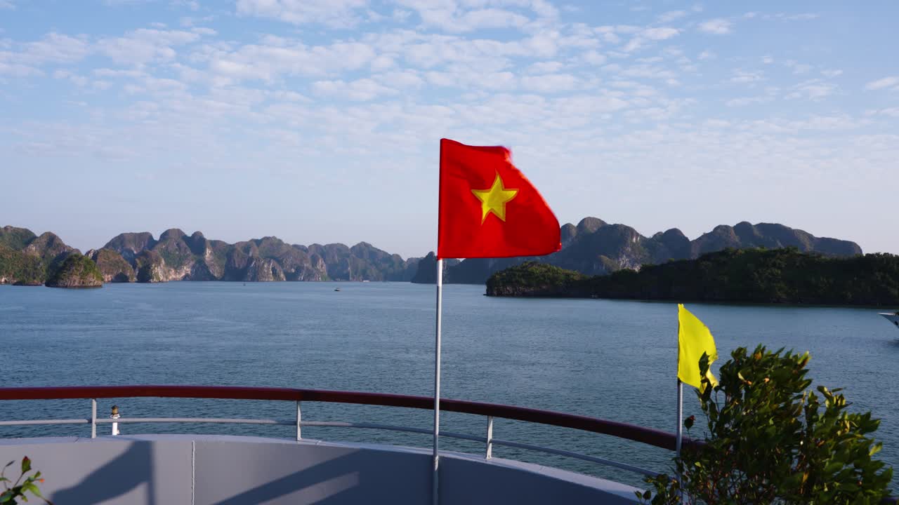 Vietnamese National Flag Waving on Deck of Cruise Ship with Ha Long Bay Limestone Mountains and Sea In Backdrop