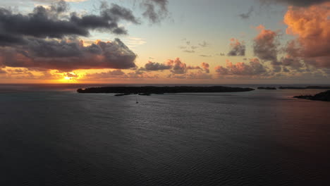bora bora, french polynesia. aerial view of sunset above island and lagoon, clouds and sun on south pacific ocean horizon
