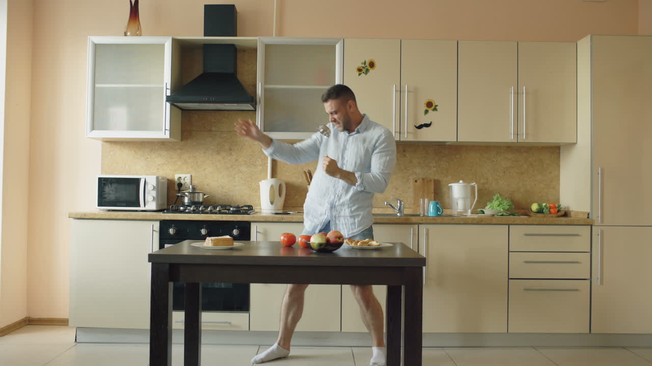 Uomo che balla e canta in cucina