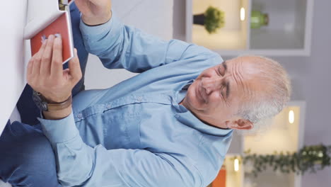 Vertical-video-of-The-old-man-looking-at-the-family-album-is-crying.