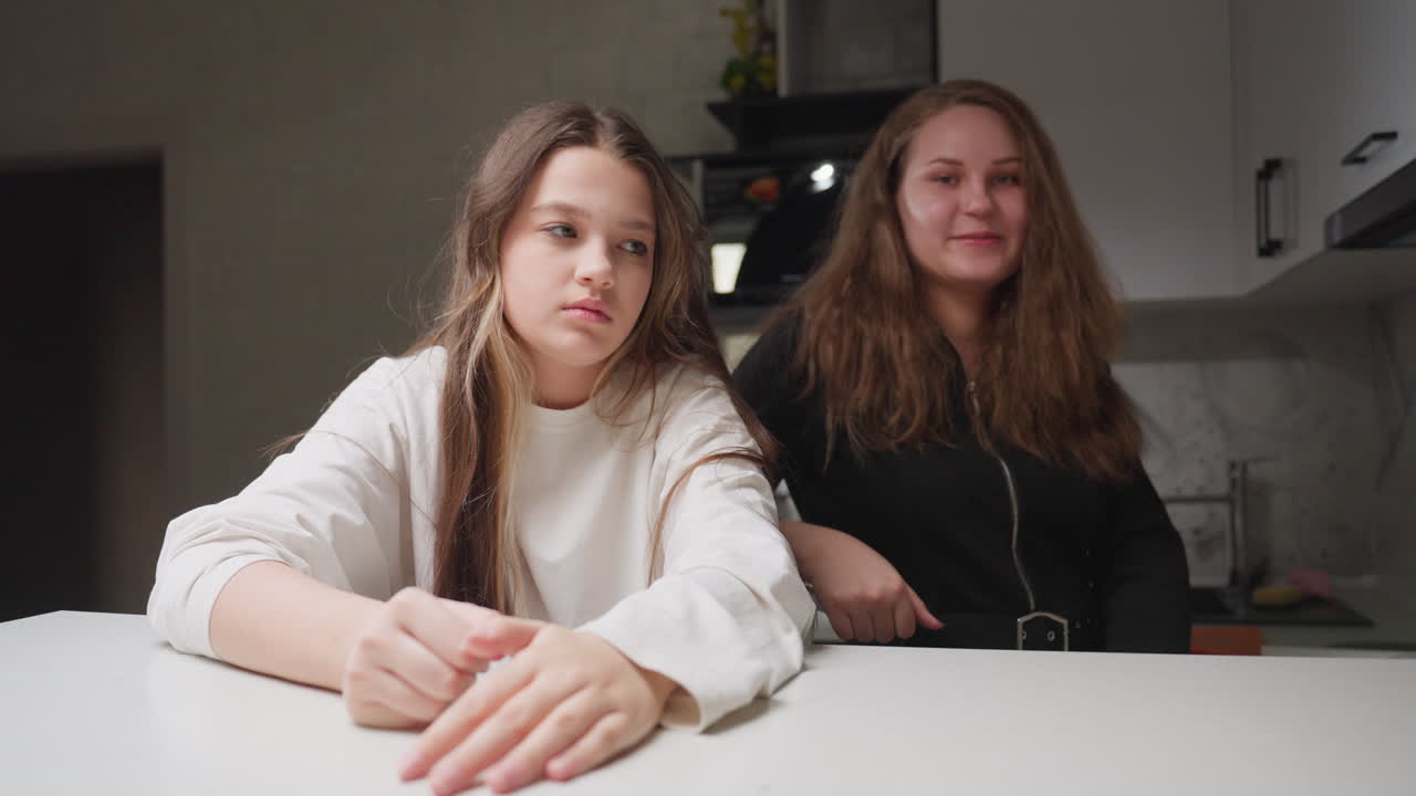 Portrait of two buddies in kitchen leaning on counter, smiling at camera, one giving thumbs up, friendly mood, warm light, casual home setting, natural expressions, long hair framing faces