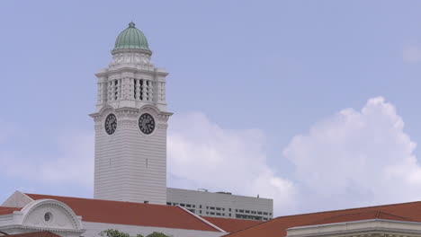 time lapse footage of a clock tower at the victoria theatre in singapore with clouds floating by a clear blue afternoon sky