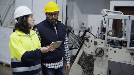 two printing technicians walking at factory with tablet