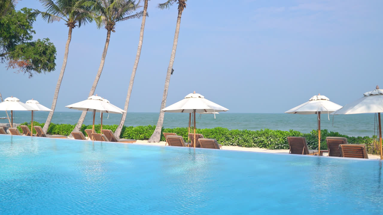 Sombrilla con piscina de cama alrededor de la piscina con fondo de mar océano - concepto de vacaciones y vacaciones