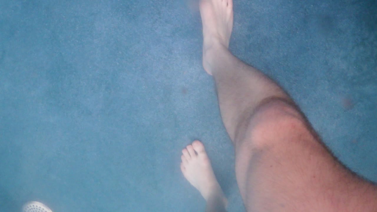 Inquadratura subacquea di persone che camminano in una piscina in un parco acquatico.