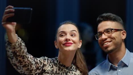 retrato de colegas usando el teléfono móvil para hacer selfies en el interior