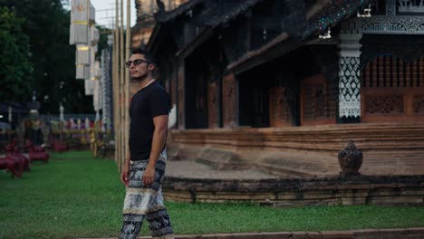 man in black shirt and printed pants at a temple in thailand