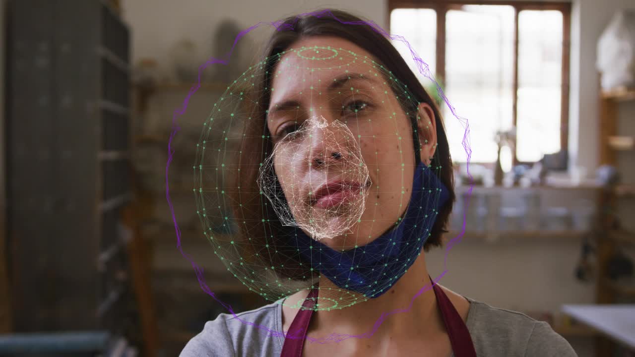 Female studio artist turning head, lowering mask and causing overlay centering on face for ceramics