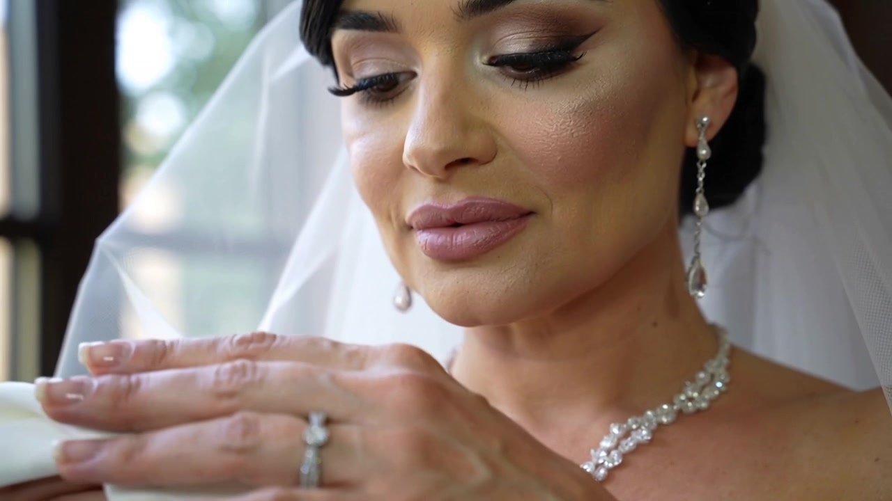 Sposa velata che si prepara, accarezzando l'anulare nella suite nuziale, con un panno bianco e un anello di diamanti.