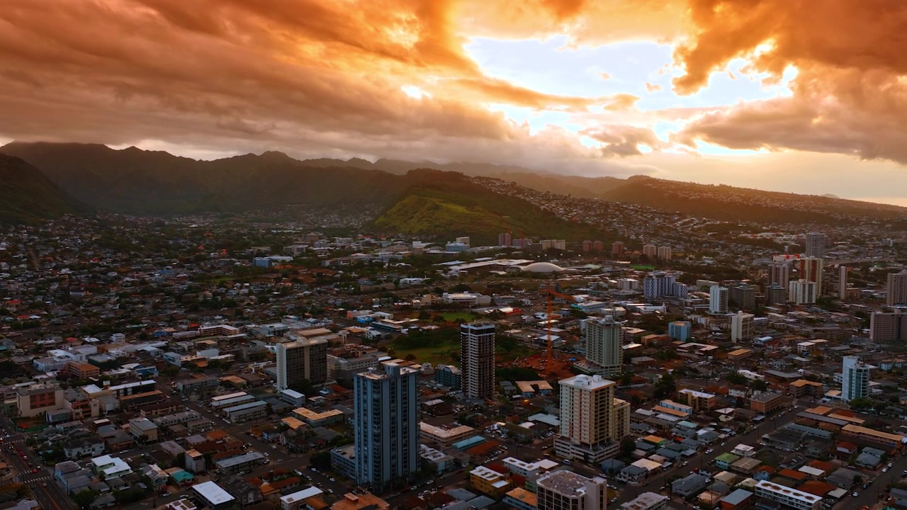 Splendido paesaggio nuvoloso arancione sopra il denso panorama urbano di Honolulu, Hawaii, USA. Catena montuosa sullo sfondo. Veduta aerea