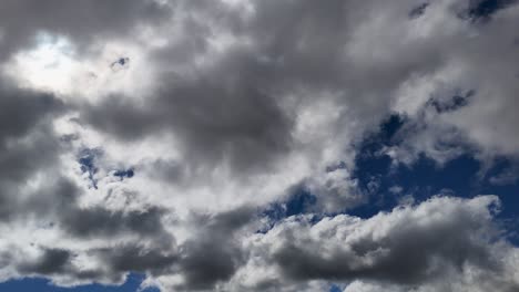 dense cumulus clouds drift rapidly across a deep blue sky in a daylight timelapse, creating dynamic lighting and a moody, atmospheric effect