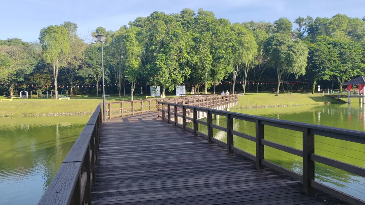 A wooden bridge gracefully spans a tranquil lake, designed exclusively for pedestrian use. This scenic walkway offers serene views of the surrounding waters.